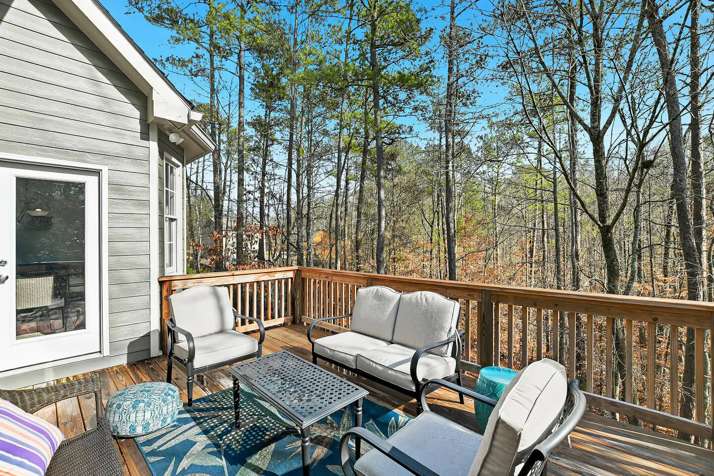 Backyard wooden deck with outdoor seating surrounded by trees